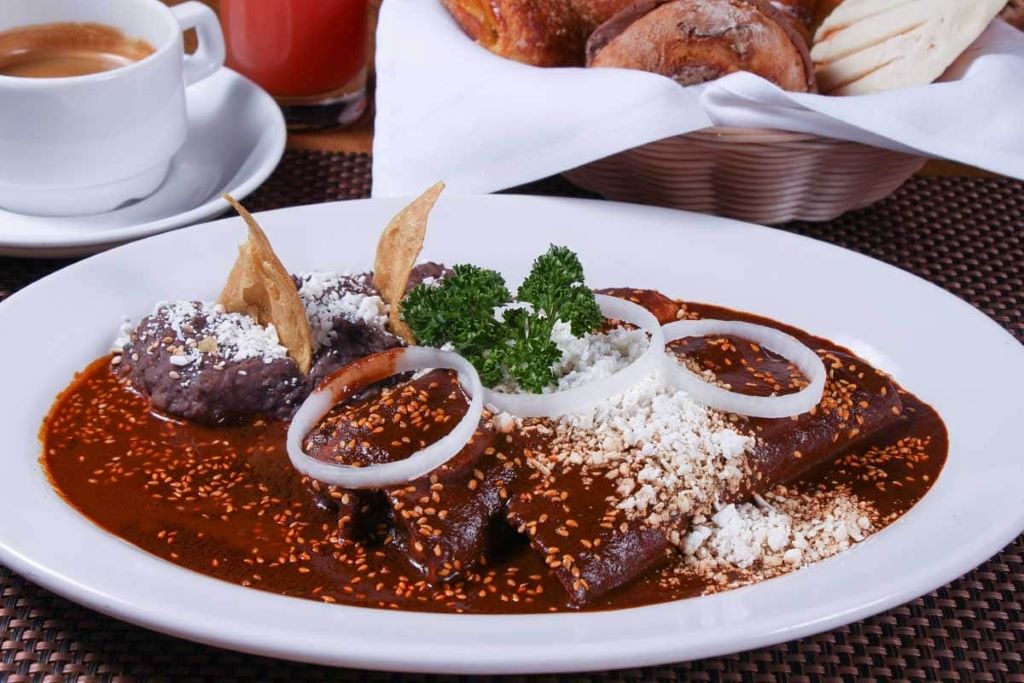 A plate of traditional Oaxacan mole negro served over chicken, garnished with sesame seeds and paired with white rice